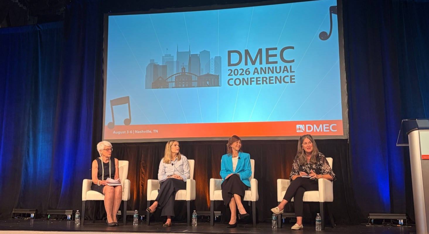 EARN&rsquo;s Susanne Bruy&egrave;re (far left) participates in a panel discussion at the 2026 DMEC Annual Conference. Four panelists are seated on stage in front of a large screen displaying the "DMEC 2026 Annual Conference" logo.