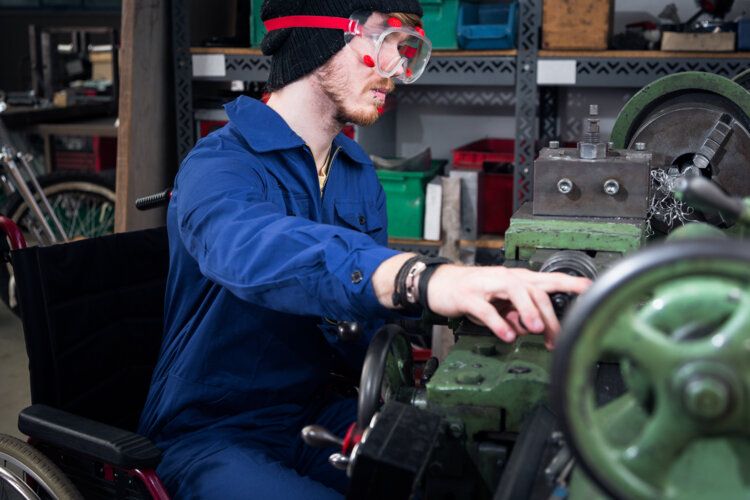 A man in a wheelchair works in a machine shop