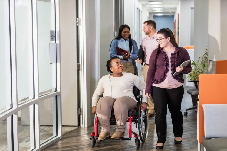 A woman in a wheelchair in an office setting with colleagues