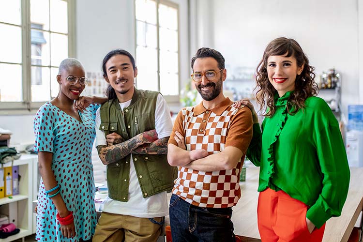 Four co-workers, one of whom has only one hand, stand together.