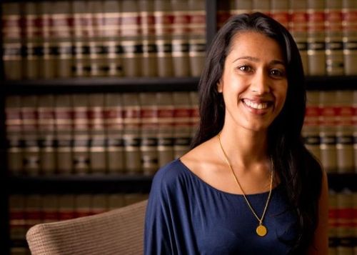 A woman standing in front of a bookshelf of law books