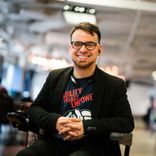 A smiling man with an earpiece sits in a wheelchair
